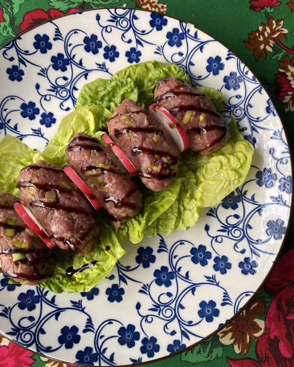 Cig kofte na liściach sałaty, na talerzu w niebieskie kwiaty