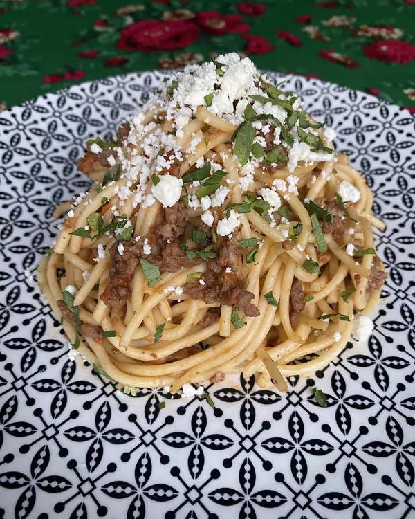 Makaron z wołowym ragu posypany owczym serem